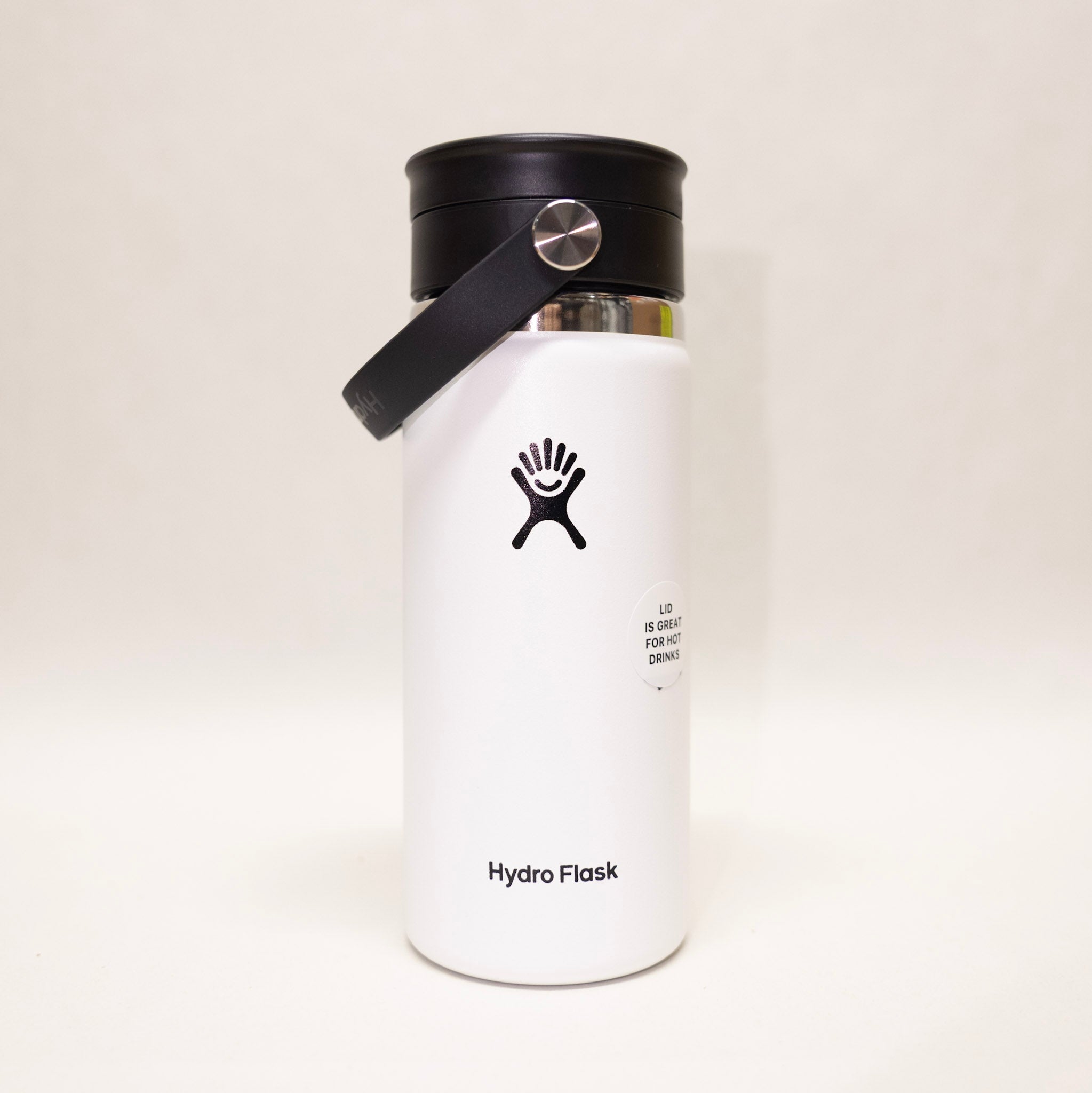 White Hydro Flask water bottle with black lid on a light beige background