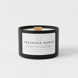 Candle with 'Absaroka Range' label on a table with white background