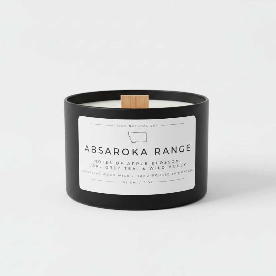 Candle with 'Absaroka Range' label on a table with white background