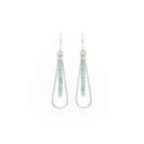 A pair of silver drop earrings with vertical rows of light blue-green rectangular beads, displayed on a textured off-white surface.