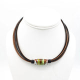 A multi-strand cord necklace with dark brown and reddish-brown cords, featuring a central glass lampwork bead with green, white, and brown marbled patterns, displayed on a white mannequin bust.