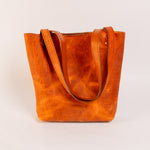 Brown leather tote bag on a light beige background