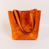 Brown leather tote bag on a light beige background