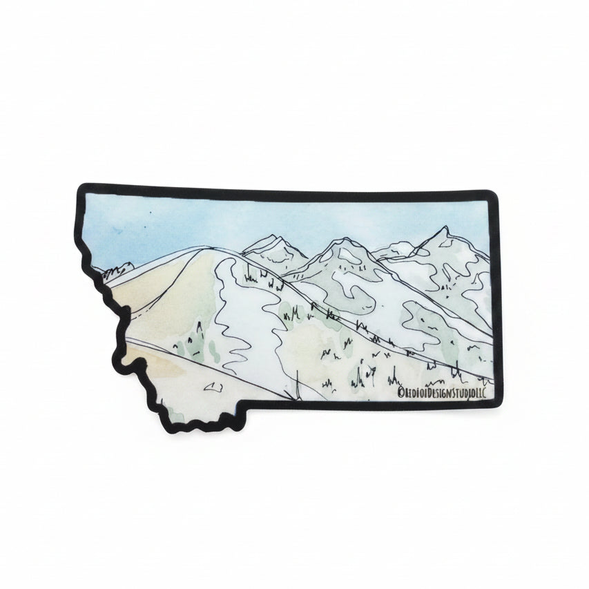 A Montana-shaped sticker or patch featuring a hand-drawn watercolor and line art mountain landscape, placed on a textured beige and white striped fabric background.