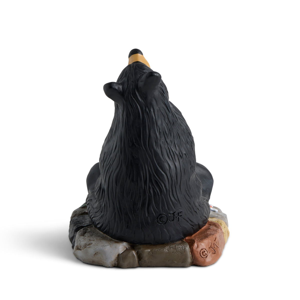 Black bear figurine sitting on a rock with a white background