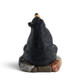 Black bear figurine sitting on a rock with a white background