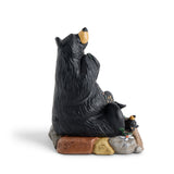 Black bear figurine sitting on a rock with a white background