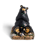 Black bear figurine with cubs holding flowers on a white background