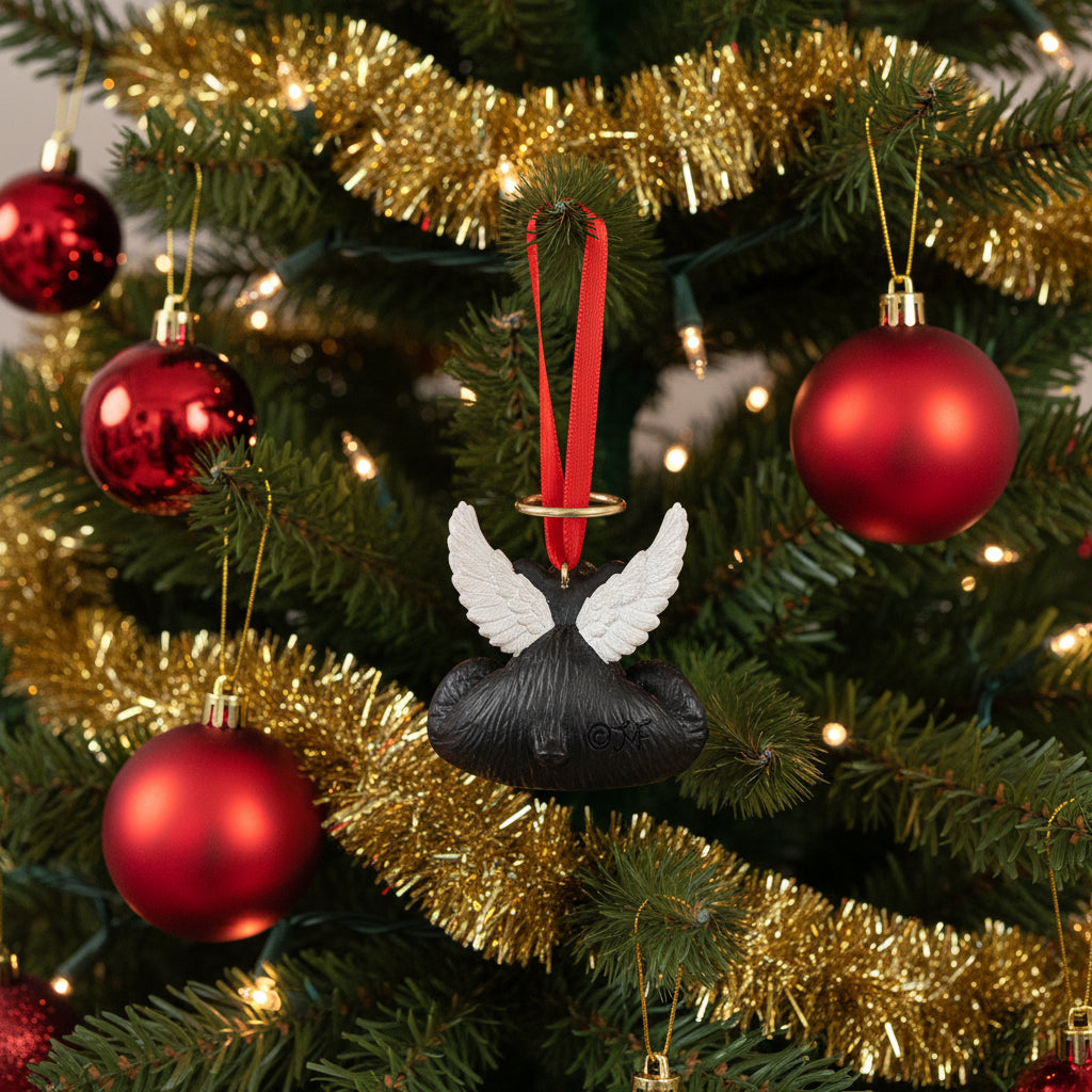 Black dog toy with white wings and a red ribbon on a white background