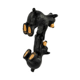 Back side of two black bear figurines hanging together