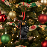 Black bear ornament with skis hanging on a decorated Christmas tree.