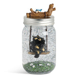 Decorative jar with a black bear on a swing inside, on a white background