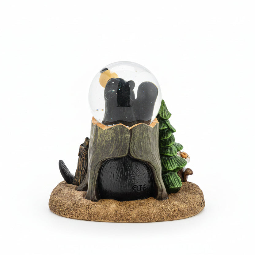 Gnome figurine inside a snow globe with a tree and log on a white background