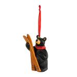 Black bear ornament with skis and a red scarf on a white background