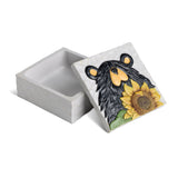 A square ceramic keepsake box with a textured light gray exterior and a decorative lid featuring a black bear face and a yellow sunflower on a white marbled background.