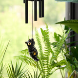 Black bear-shaped wind chime hanging among green plants