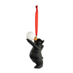 Bear ornament holding a volleyball with a red string on a white background