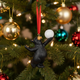 Black bear ornament holding a white ball on a Christmas tree with colorful ornaments.