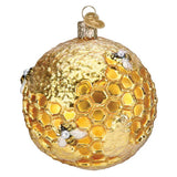 Gold Christmas ornament with honeycomb design and bees on a white background