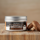Olivelle Black Garlic Shiitake rub & seasoning container on a wooden surface with mushrooms.