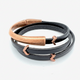 Black leather bracelet with rose gold accents on a white background