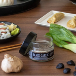 Assorted Asian cuisine including dumplings, sushi, and black garlic on a wooden table.