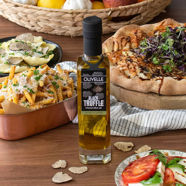 Olivelle Black Truffle oil bottle with a variety of food items on a wooden table