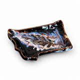 An Montana shaped ceramic dish with a glossy black glaze, featuring a marbled pattern of white, blue, and brown swirls, and a rustic copper-brown rim, shown on a plain white background.
