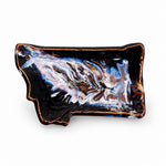 An Montana shaped ceramic dish with a glossy black glaze, featuring a marbled pattern of white, blue, and brown swirls, and a rustic copper-brown rim, shown on a plain white background.