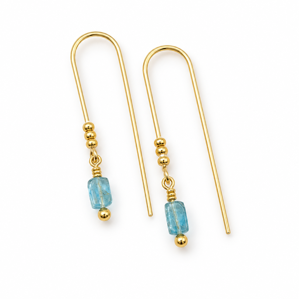 A pair of gold drop earrings with a faceted light blue bead and a small gold bead below, shown on a plain white background.