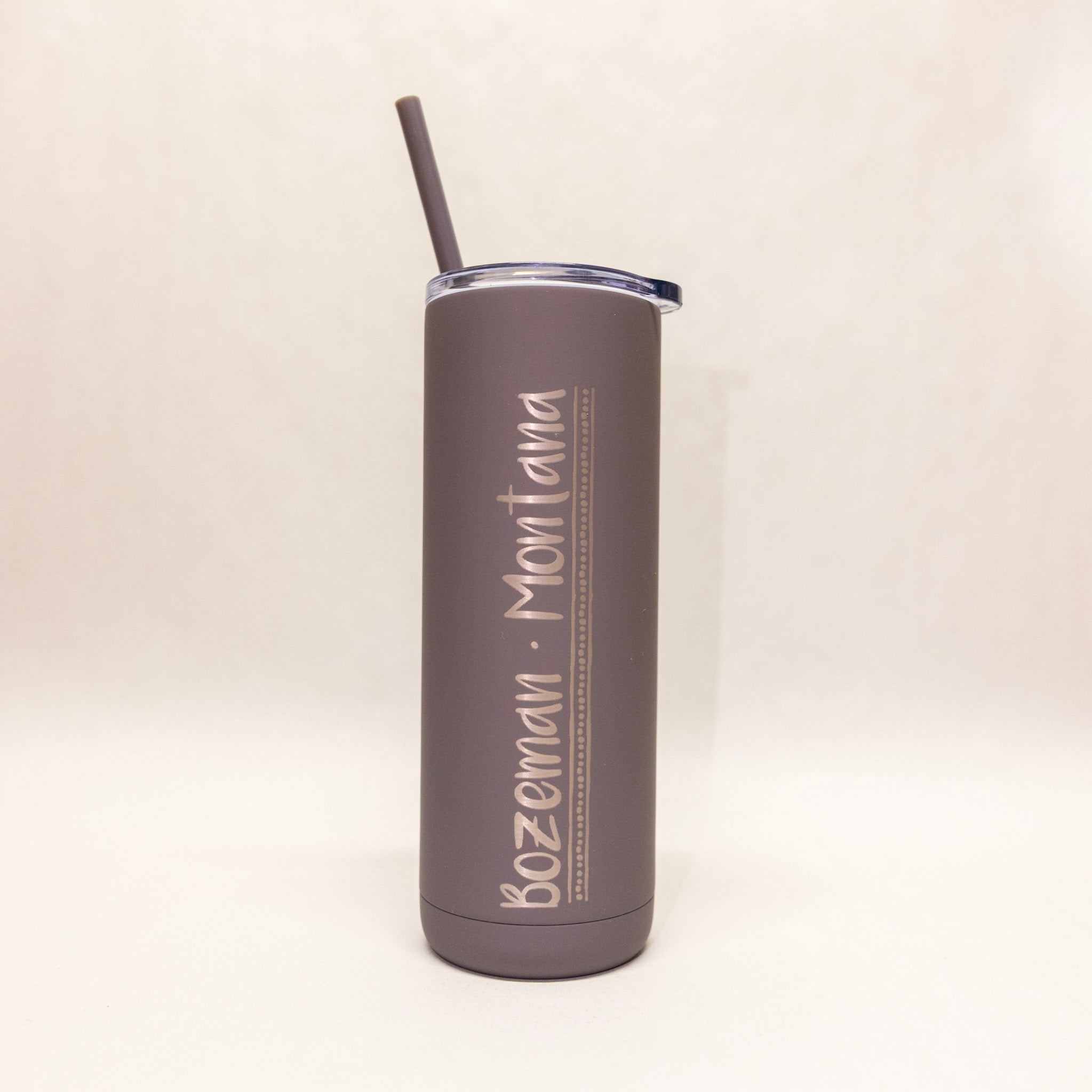 Gray tumbler with 'Bozeman, Montana' text on a beige background