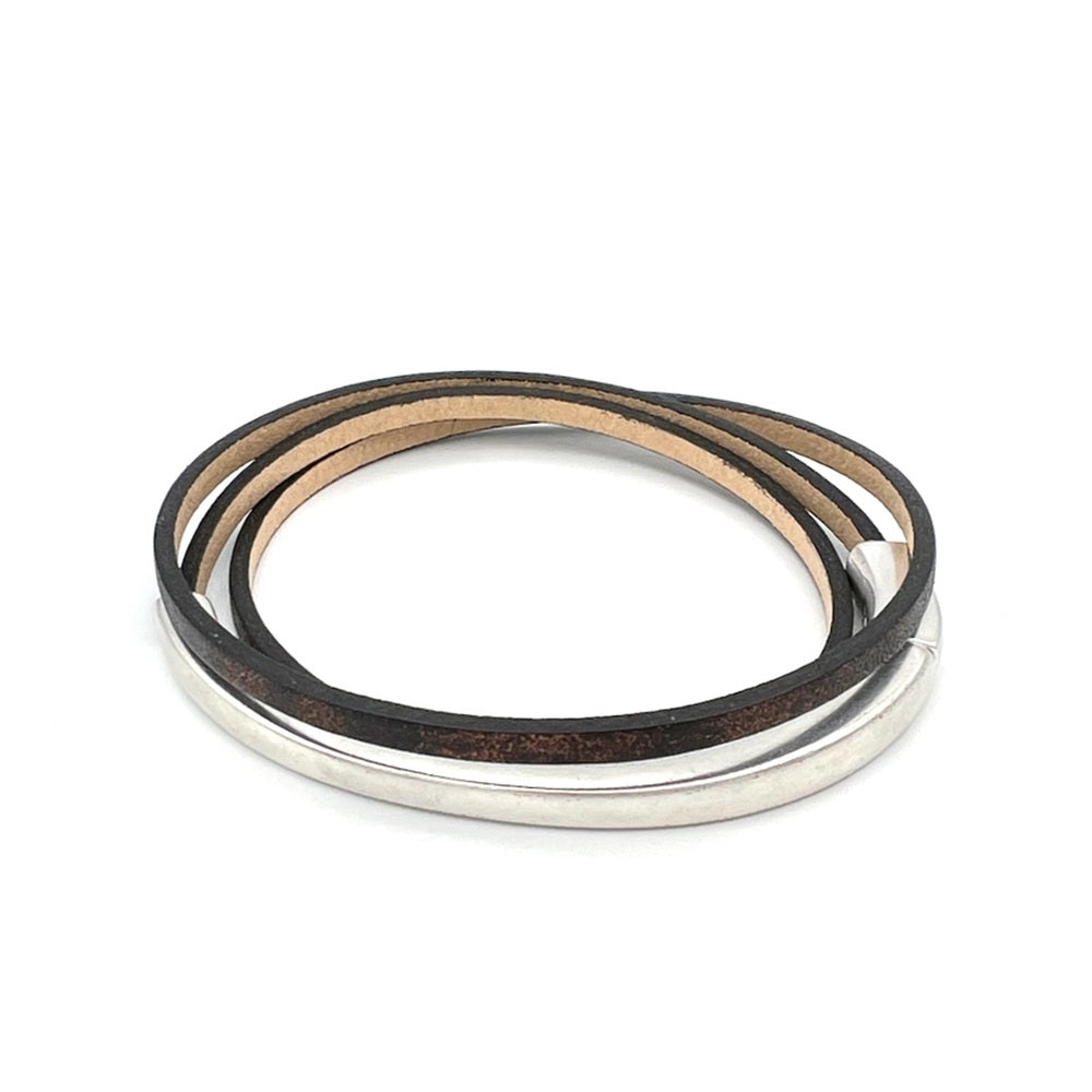 A multi-layered wrap bracelet featuring dark brown leather, a thin tan leather layer, and a polished silver metal bangle, displayed on a clean white background.