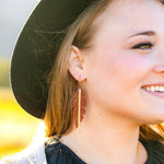 Woman wearing a black hat and earrings with a blurred natural background