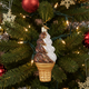 Christmas ornament shaped like a waffle cone with ice cream on a decorated tree.