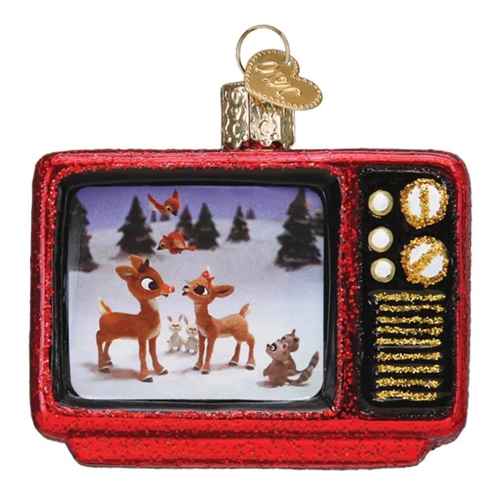 A red glitter Christmas ornament shaped like a retro television set, with a hanging loop and gold ornament tag. The screen displays a festive winter scene with reindeer and a squirrel, while the right side features gold speaker-grill details and white control buttons on a black background.