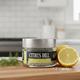 Jar of Citrus Dill infused sea salt on a wooden surface with a lemon and dill sprig.