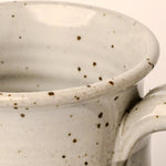 Close-up of a ceramic mug with speckled pattern on a neutral background