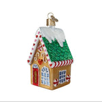 Decorative gingerbread house ornament with a green roof and red door on a white background