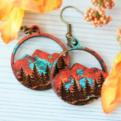 Pair of earrings with nature-themed design on a light blue background with flowers.