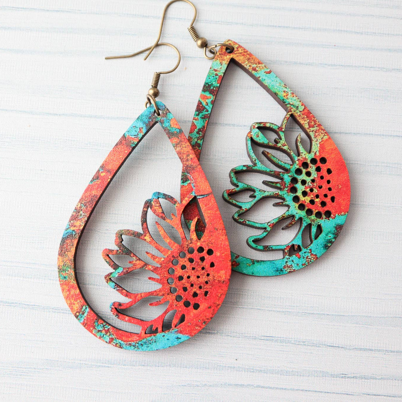 Pair of colorful teardrop-shaped earrings on a light wooden surface
