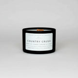 Candle labeled 'Country Crush' on a marble surface with a blurred background