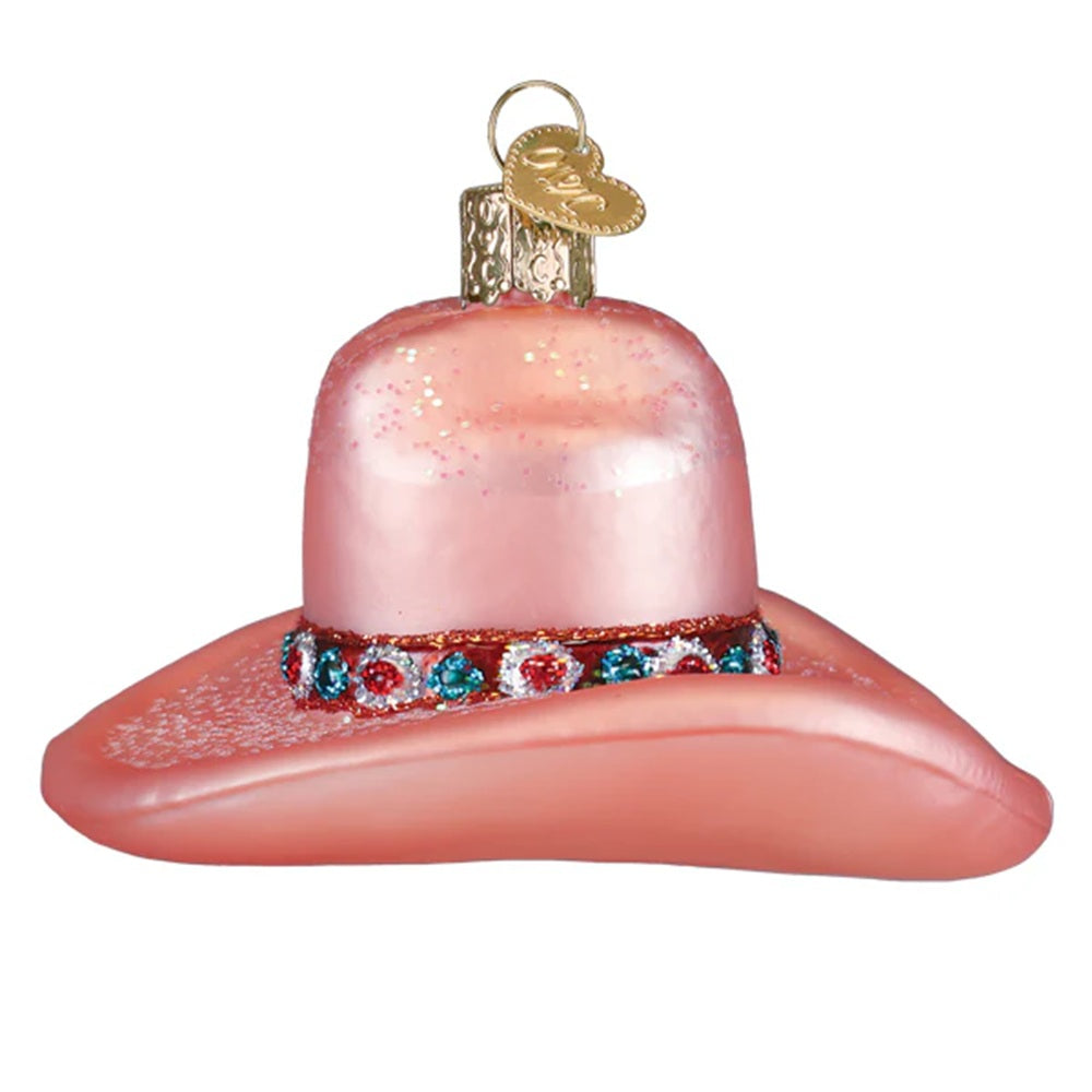 Pink glass cowboy hat ornament with decorative band on a white background