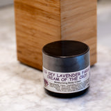 Wooden soap dispenser with a cylindrical container labeled 'Cream of the Crop' on a textured surface.