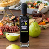 Olivelle Crisp Anjou Pear balsamic vinegar bottle on a table with fruits and meats.