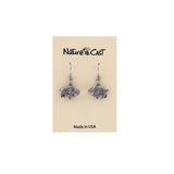 A pair of silver-toned buffalo dangle earrings displayed on a beige Nature's Cast brand card that reads 'Made in USA'.