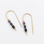 A pair of gold-tone drop earrings with small cylindrical beads in purple, blue, and black, displayed on a clean white background.