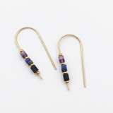 A pair of gold-tone drop earrings with small cylindrical beads in purple, blue, and black, displayed on a clean white background.