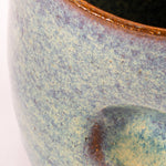 Close-up of a ceramic mug with speckled glaze and brown rim