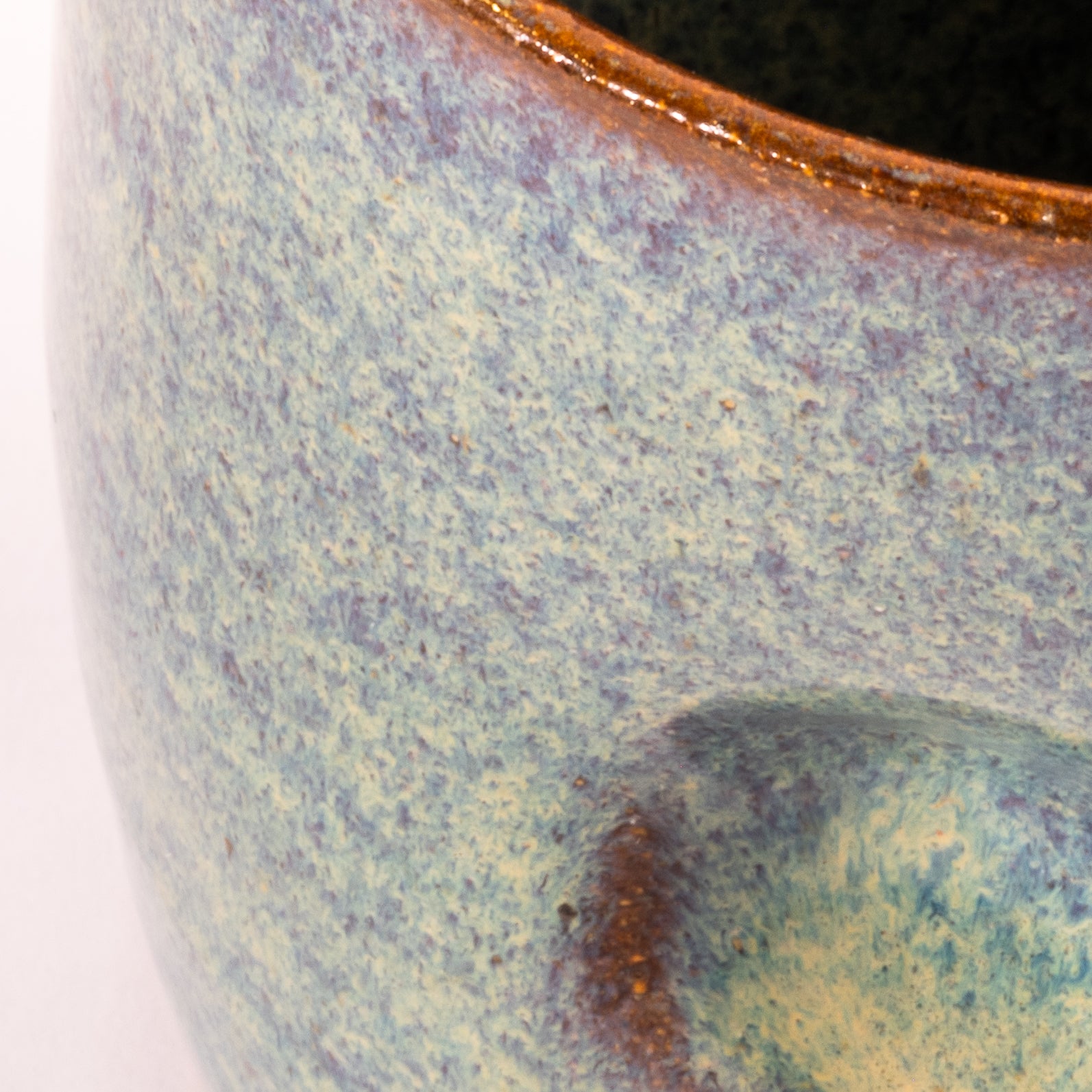 Close-up of a ceramic mug with speckled glaze and brown rim