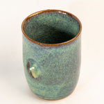 Green ceramic cup with brown rim on a white background
